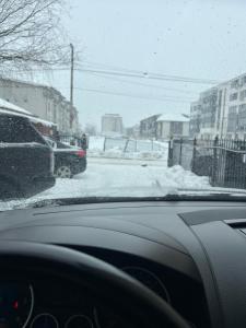 a car is driving down a snow covered street at Lux studio 46 meters in Colentina