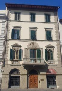 a tall white building with green shuttered windows at La Luna Guest House in Florence