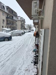 a snow covered street with cars parked on the side of a building at Lux studio 46 meters in Colentina