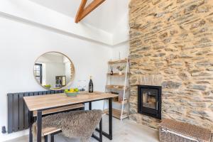 a dining room with a stone wall and a table and a fireplace at Cosy Nook at Jam Jar Kitchen in Crantock