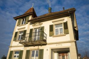 a tall white building with green shutters and a balcony at Studio Frohburg Gommiswald in Gommiswald