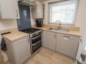 a kitchen with white cabinets and a stove and a sink at Cresswell Towers in Morpeth +11 photos
