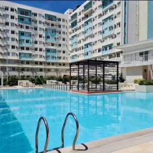 a swimming pool in front of a large apartment building at Kurt Condo Rental Simple & Cozy in Piapi