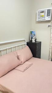 a bed with a pink pillow and a air conditioner at Kurt Condo Rental Simple & Cozy in Piapi +13 photos
