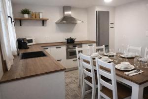 a kitchen with a table with white chairs and a kitchen with a kitchen at VIVIENDA RURAL PEROTXENEA LANDETXEA para familias y grupos de amigos con jardín y barbacoa in Doneztebe