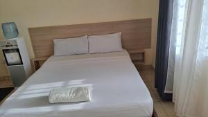 a large white bed with a pillow on it at Diani Haven Swahili modern studio in Kwale