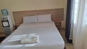 a white bed with a pillow on top of it at Diani Haven Swahili modern studio in Kwale
