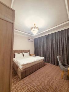 a bedroom with a large bed and a chandelier at Volidam Hotel in Qarshi +22 photos