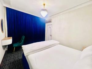a room with two beds and a blue curtain at Volidam Hotel in Qarshi