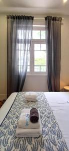 a bedroom with a bed with towels and a window at 1000Jo Apartment T3 in Gulpilhares
