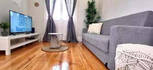 a living room with a gray couch and a television at 1000Jo Apartment T3 in Gulpilhares