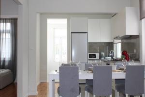 a kitchen with a table with chairs and a kitchen with white cabinets at 1000Jo Apartment T3 in Gulpilhares