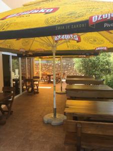 a large yellow umbrella sitting next to wooden benches at Hostel **Casa del Sole** in Klenovica