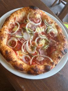 a pizza sitting on a white plate on a table at Hostel **Casa del Sole** in Klenovica +19 photos
