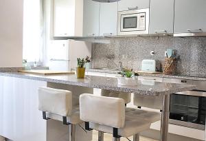 a kitchen with white cabinets and a counter with chairs at Arrábida Luxury Studio in Vila Nova de Gaia