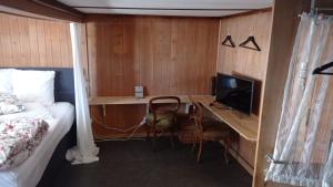 a bedroom with a bed and a desk with a television at Swiss Mountain Chalet in Saxeten
