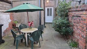 a table with chairs and an umbrella on a patio at Double rooms in Crosby