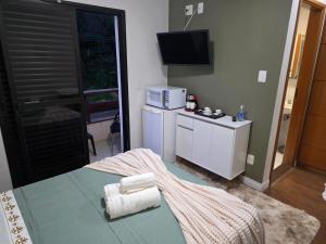 a room with a bed and a kitchen with a television at Flat 108B com lazer próx ao centro in Serra Negra +12 photos