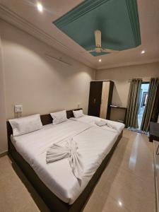 a bedroom with a large white bed with a ceiling at Hotel Maharaja Path in Ujjain