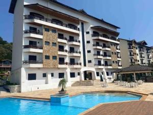 a large building with a swimming pool in front of it at Flat 108B com lazer próx ao centro in Serra Negra