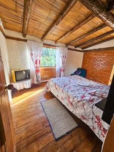 a bedroom with a bed and a tv in a room at Cabaña Bachué in Sutatausa