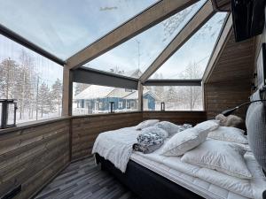 a bed in a room with a large window at Panorama Iglu Hankasalmi Resort in Hankasalmi