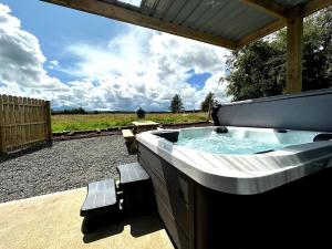a large hot tub in a backyard with a wooden roof at The Lux Pod in Ballynameen