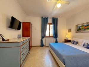 a bedroom with a bed and a dresser with a television at 49 Sea Rooms - Guesthouse by Host Hero in Stintino