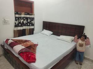 a little girl standing next to a large bed at Pushpkali Seva Sadan in Mathura