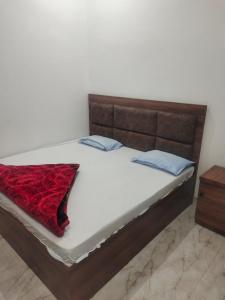 a bed with a wooden frame and a red blanket on it at Pushpkali Seva Sadan in Mathura