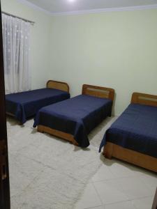 three beds in a room with blue sheets at Valbona in Korçë