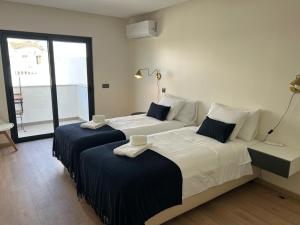 two beds in a hotel room with a window at Casa aOrta Apartments in Faro