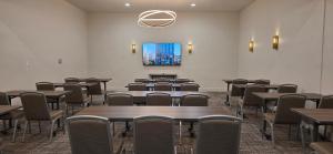a room with tables and chairs and a tv on the wall at Rayland Hotel in The Dalles