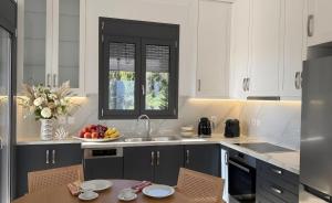 a kitchen with white cabinets and a table with a bowl of fruit at 360 Skyline Suite, Argostoli in Argostoli
