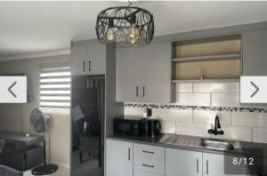 a kitchen with white cabinets and a chandelier at Lemao guesthouse in Johannesburg