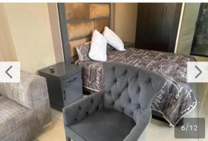 a bedroom with a bed with a chair and a couch at Lemao guesthouse in Johannesburg