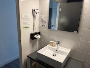 a bathroom with a sink and a phone on the wall at Cit'Hotel Logis Le Chêne Vert in Les Sables-d'Olonne +34 photos