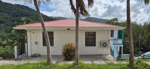 a white house with a red roof and palm trees at Villas De Morne St Lucia in Grande Rivière