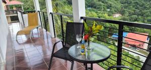a balcony with a table with glasses and flowers on it at Villas De Morne St Lucia in Grande Rivière +4 photos