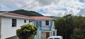 a white house with a blue balcony and a truck at Villas De Morne St Lucia in Grande Rivière
