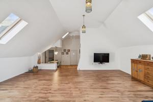 an attic living room with white walls and a flat screen tv at Natururlaub Eifel-Mandala Feriewohnung in Kall