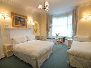 Habitación de hotel con 2 camas y mesa en St Ann’s Guest House, en Inverness