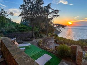 a backyard with a green lawn with a sunset at Villa Velta Calagrande in Porto Santo Stefano