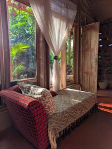 a bedroom with a couch and a window in a room at Backyard Eco Bungalows Moshi in Moshi