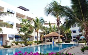 a pool in front of a hotel with palm trees at Appartement à Natangue 1 in Saly Portudal