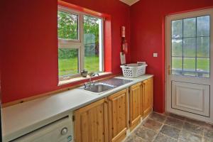 a kitchen with red walls and a sink and windows at 3 Bed in Portmagee oc-i172 in Valentia Island +17 photos