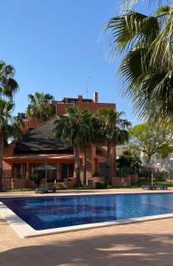 a swimming pool in front of a building with palm trees at Penthouse Palapagolf in Orihuela Costa