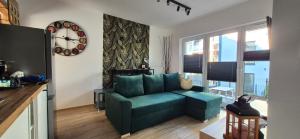 a living room with a green couch and a clock at Izzy Apartament in Myślenice