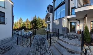 a house with a stone walkway next to a building at Izzy Apartament in Myślenice