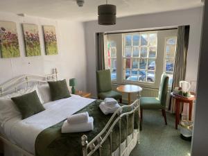 a bedroom with a bed and two chairs and a window at The Phelips Arms in Montacute